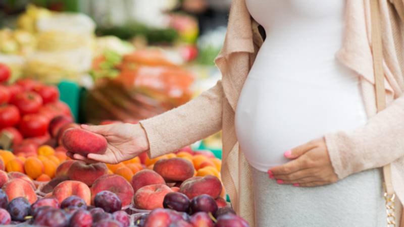 Zwangere vrouw koopt gezond eten op de markt