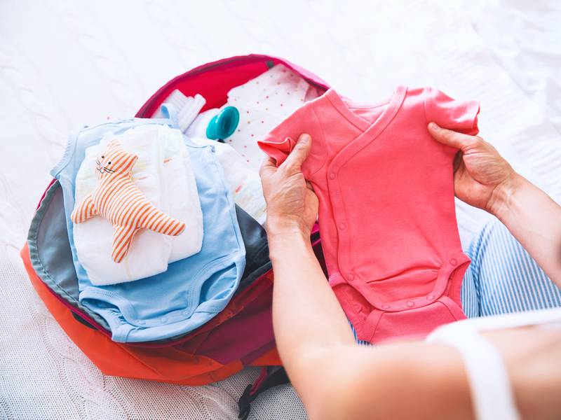 Vrouw pakt vluchtkoffer in met babykleertjes